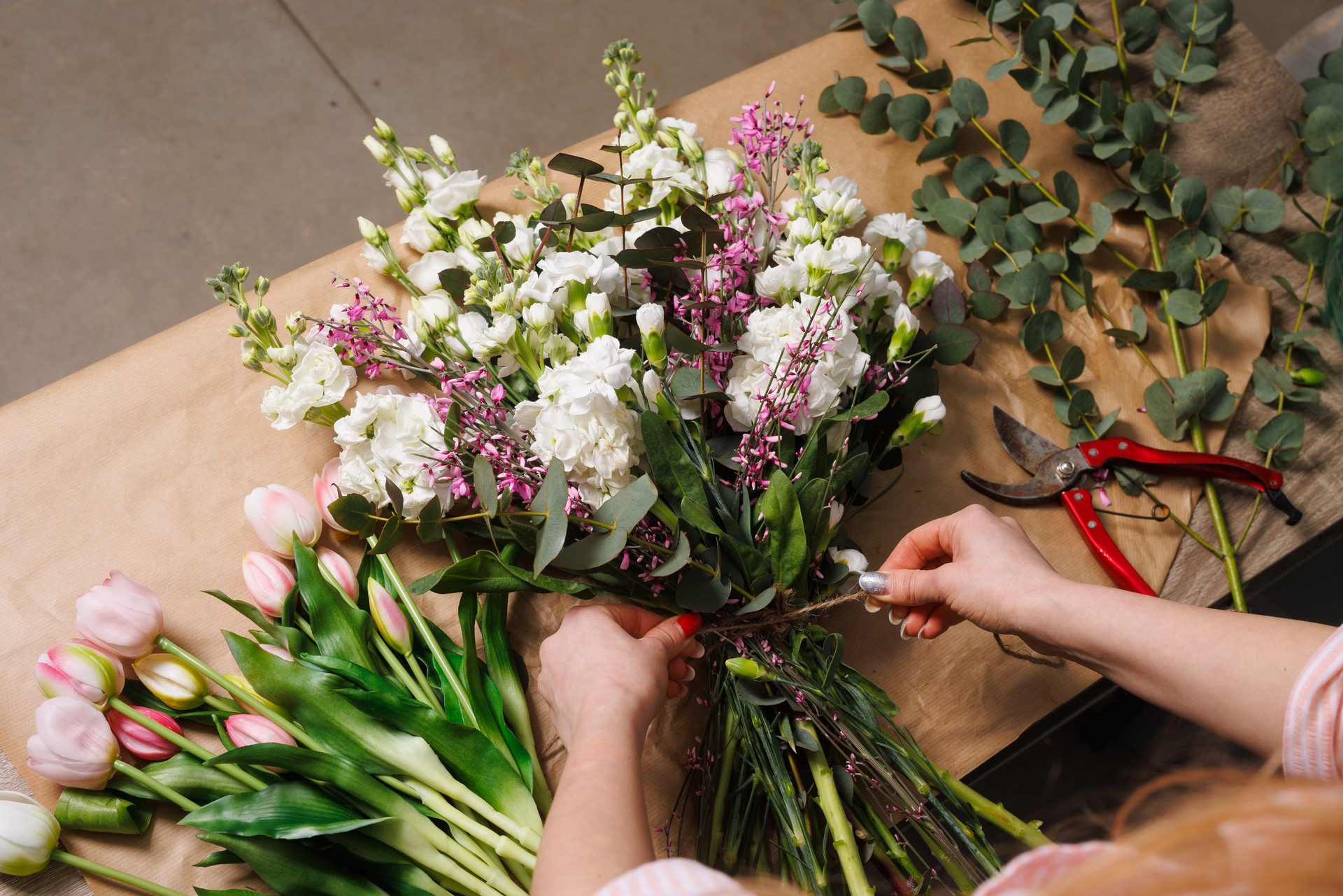 female florist makes a bouquet in a flower shop, spring bouquet